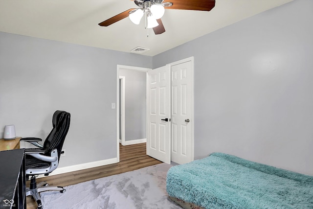 bedroom featuring baseboards, wood finished floors, an office area, and ceiling fan