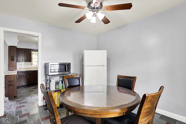 dining room with a ceiling fan and baseboards