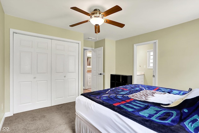 carpeted bedroom featuring a closet, ensuite bath, a ceiling fan, and baseboards