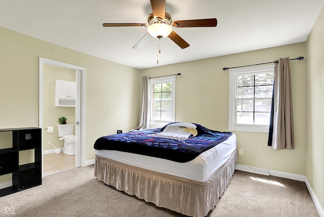 carpeted bedroom with connected bathroom, baseboards, and ceiling fan