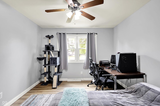 bedroom with wood finished floors, baseboards, an office area, and a ceiling fan