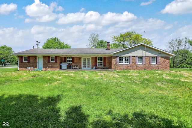 ranch-style home with french doors, brick siding, a chimney, and a front lawn