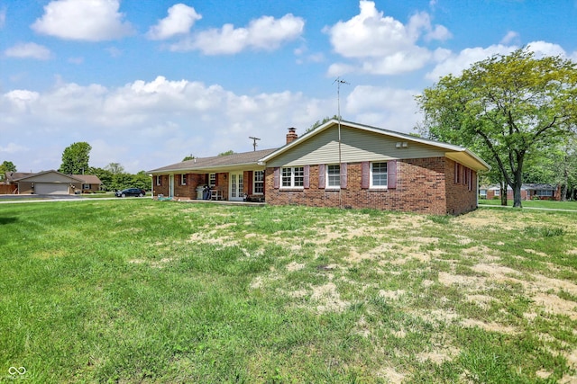 back of house with brick siding, a lawn, and a chimney
