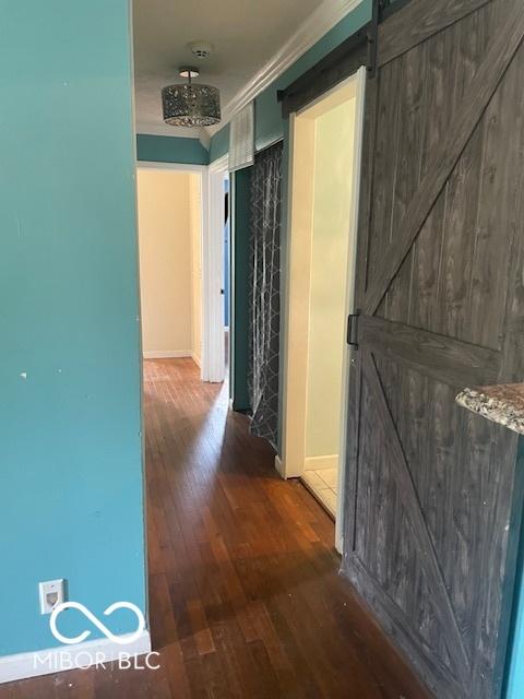 5802 Bertha St, Indianapolis, IN 46241 - hallway featuring a barn door, hardwood / wood-style floors, baseboards, and ornamental molding