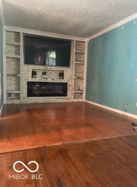 5802 Bertha St, Indianapolis, IN 46241 - unfurnished living room featuring a glass covered fireplace, a textured ceiling, ornamental molding, built in shelves, and wood-type flooring