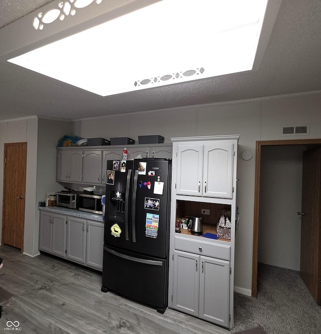 5269 W State Road 42, Brazil, IN 47834 - kitchen with black refrigerator with ice dispenser, stainless steel microwave, a skylight, crown molding, and white cabinetry