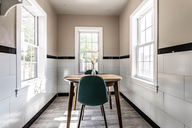 5428 E 10th St, Indianapolis, IN 46219 - dining space featuring wood finished floors, tile walls, and a wainscoted wall