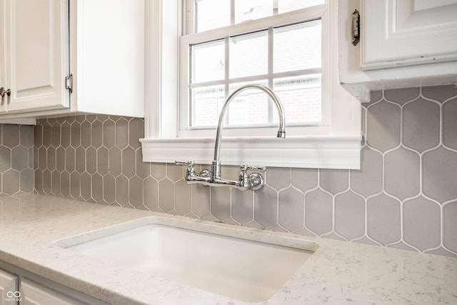 5428 E 10th St, Indianapolis, IN 46219 - kitchen view of a sink, tasteful backsplash, white cabinetry, and light stone countertops