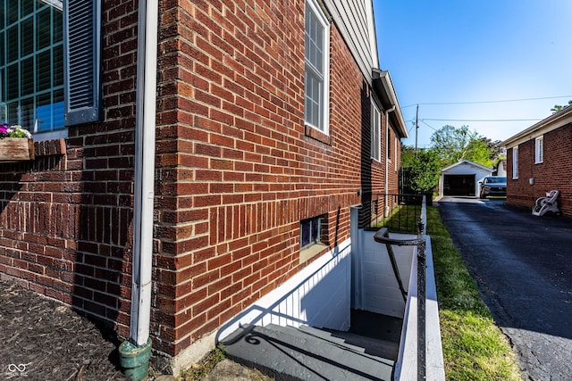 5428 E 10th St, Indianapolis, IN 46219 - view of property exterior with brick siding, asphalt driveway, and a detached garage