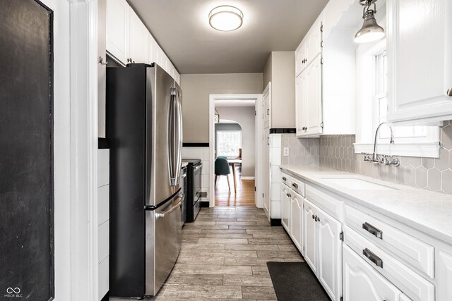 5428 E 10th St, Indianapolis, IN 46219 - kitchen with appliances with stainless steel finishes, a sink, white cabinetry, light wood finished floors, and light countertops