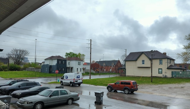 view of asphalt road featuring a residential view, traffic signs, and curbs