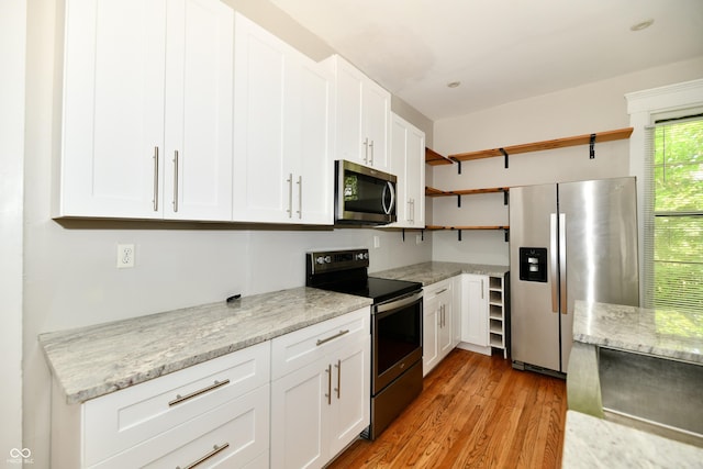 631 Prospect St, Indianapolis, IN 46203 - kitchen featuring stainless steel appliances, open shelves, white cabinetry, light wood-style floors, and light stone counters