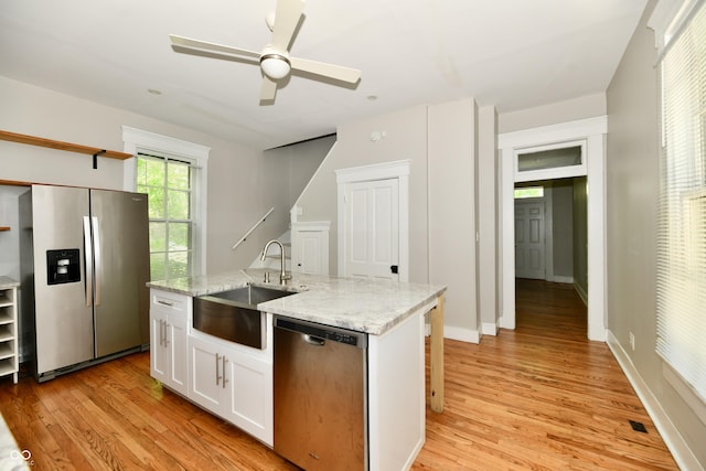 631 Prospect St, Indianapolis, IN 46203 - kitchen with appliances with stainless steel finishes, light wood finished floors, open shelves, white cabinetry, and light stone counters