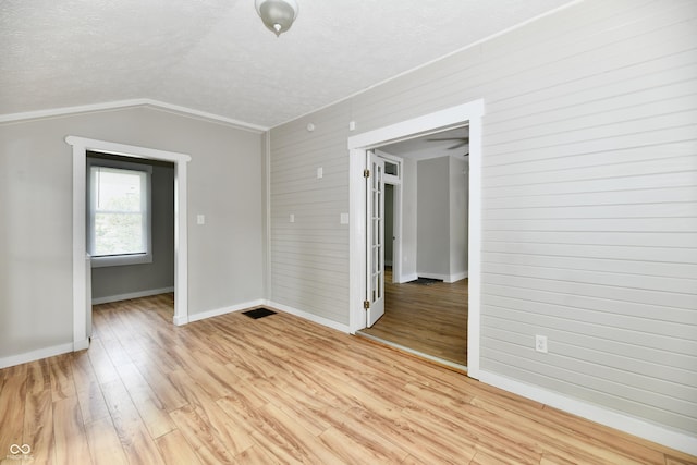 631 Prospect St, Indianapolis, IN 46203 - unfurnished room with light wood-style flooring, a textured ceiling, wooden walls, and vaulted ceiling
