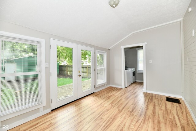 631 Prospect St, Indianapolis, IN 46203 - spare room featuring separate washer and dryer, lofted ceiling, light wood-type flooring, french doors, and a textured ceiling