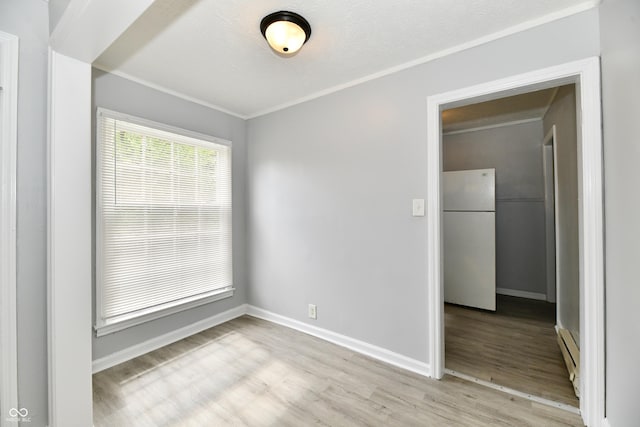 2966 N Olney St, Indianapolis, IN 46218 - empty room featuring wood finished floors, baseboards, baseboard heating, and ornamental molding