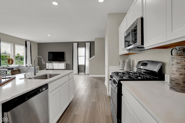 kitchen featuring stainless steel appliances, a sink, open floor plan, healthy amount of natural light, and recessed lighting