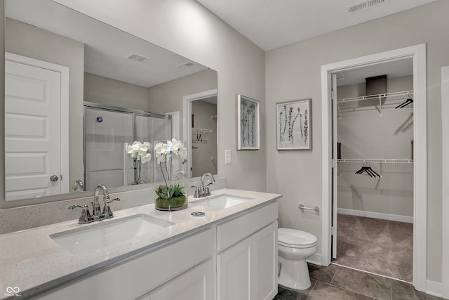 full bathroom featuring a stall shower, toilet, a walk in closet, and double vanity