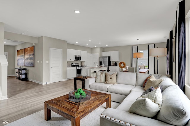 living area with light wood finished floors, baseboards, and recessed lighting