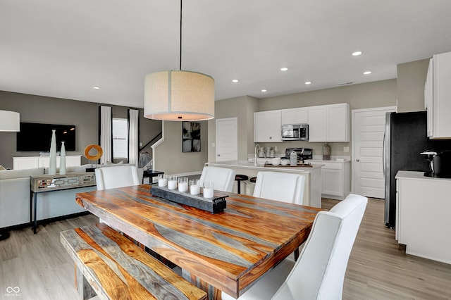 dining space with light wood finished floors, recessed lighting, and stairs