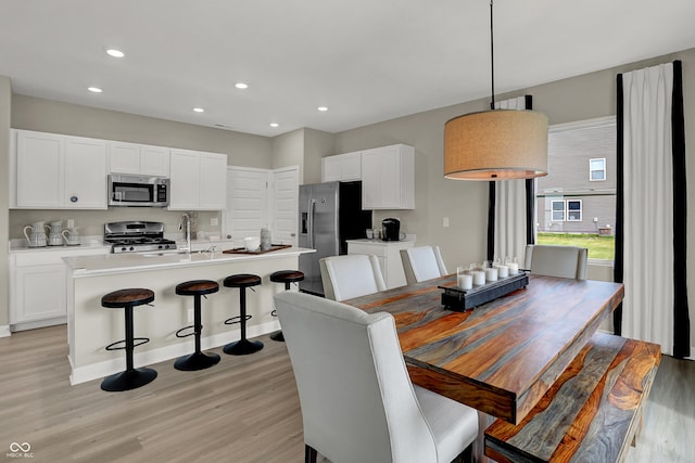 dining room with light wood-type flooring, recessed lighting, and baseboards