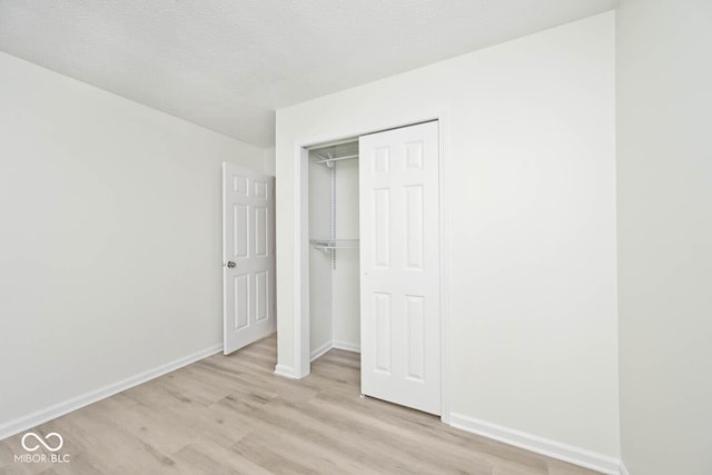 19446 Ethan Allen Ln, Westfield, IN 46074 - unfurnished bedroom with light wood-type flooring, a closet, baseboards, and a textured ceiling