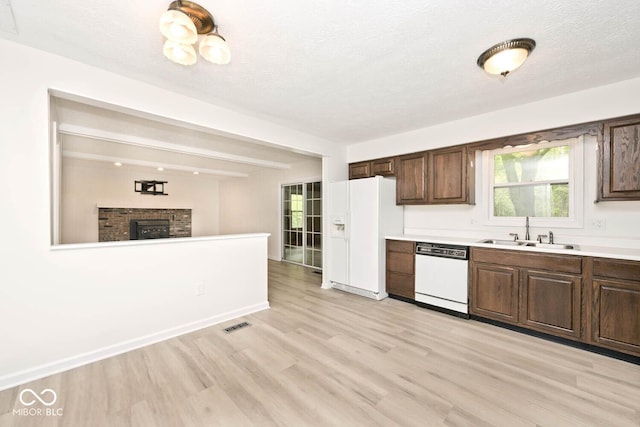 19446 Ethan Allen Ln, Westfield, IN 46074 - kitchen featuring white appliances, a sink, light wood finished floors, light countertops, and a fireplace