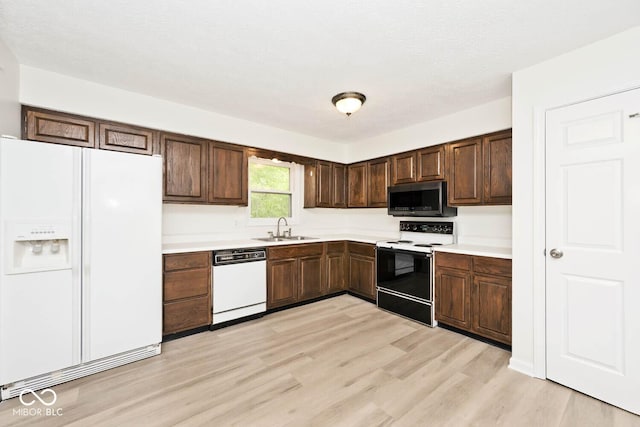 19446 Ethan Allen Ln, Westfield, IN 46074 - kitchen with white appliances, a sink, light wood-style floors, light countertops, and dark brown cabinetry