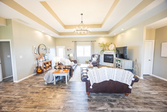 living room featuring wood finished floors, a tray ceiling, baseboards, a chandelier, and recessed lighting