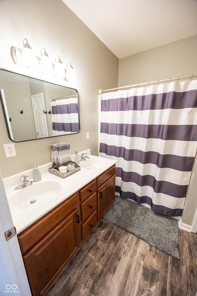 bathroom featuring wood finished floors, double vanity, and a shower with curtain