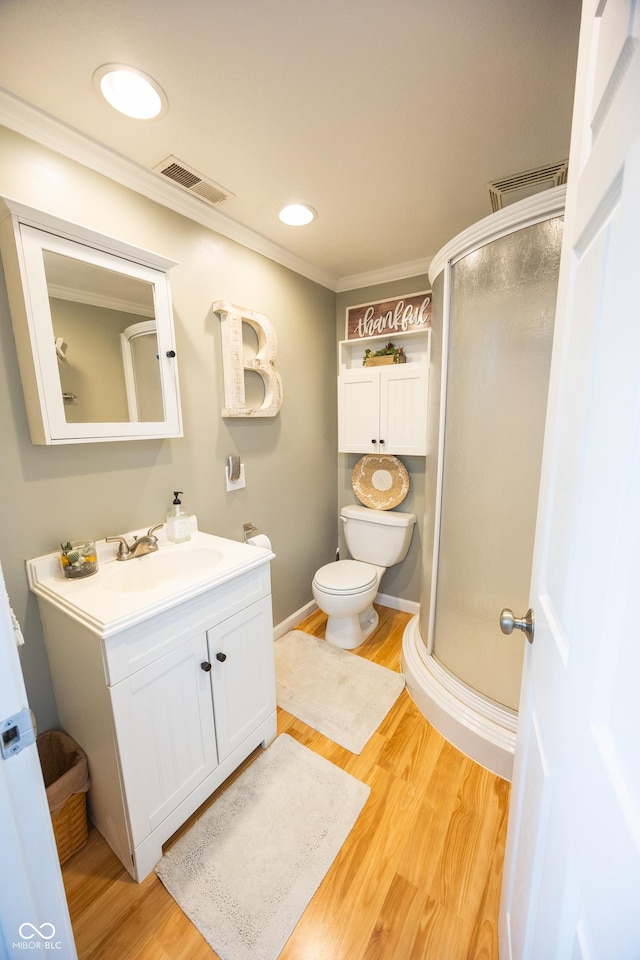 bathroom with a shower stall, ornamental molding, wood finished floors, vanity, and toilet