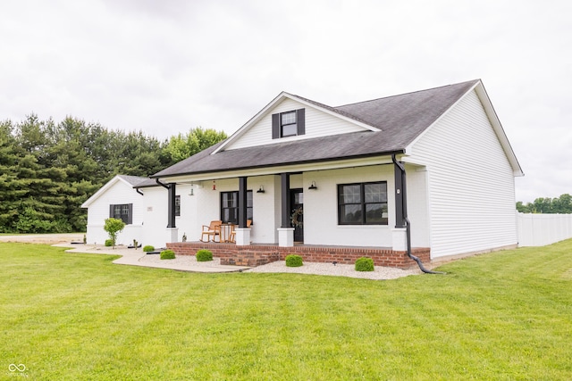 view of front of house with a porch, a front yard, a shingled roof, and brick siding