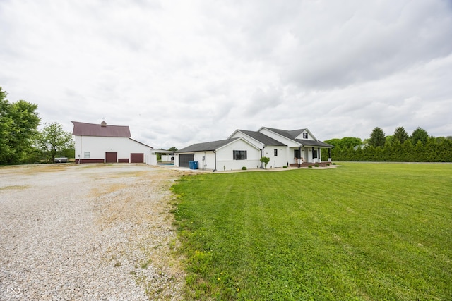 view of front facade featuring driveway, a front yard, a garage, an outdoor structure, and covered porch