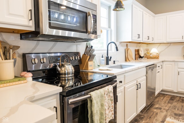 kitchen featuring stainless steel appliances, a sink, white cabinets, and dark wood-style flooring