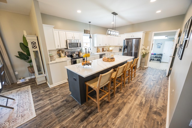 kitchen featuring appliances with stainless steel finishes, dark wood-style flooring, white cabinets, a kitchen bar, and a kitchen island