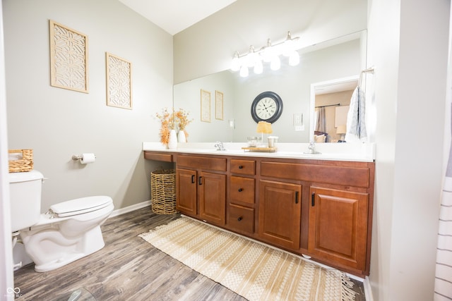 full bathroom with toilet, wood finished floors, double vanity, and baseboards
