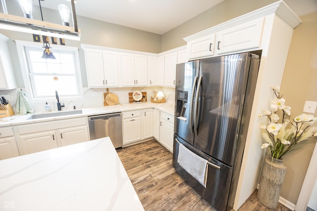 kitchen with stainless steel appliances, a sink, wood finished floors, and white cabinetry