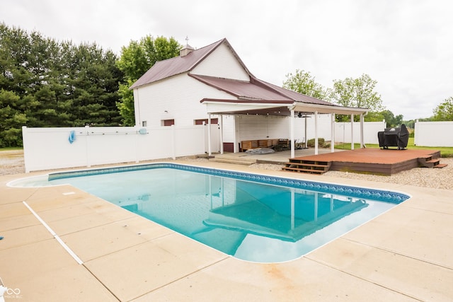 view of swimming pool featuring a wooden deck, fence, and a patio