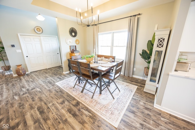 dining area featuring wood finished floors, a chandelier, baseboards, and a tray ceiling