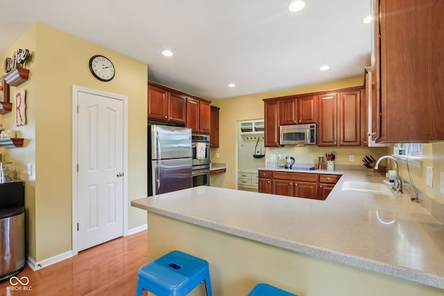 9311 Windrift Way, Zionsville, IN 46077 - kitchen featuring appliances with stainless steel finishes, a peninsula, light countertops, light wood-style floors, and recessed lighting