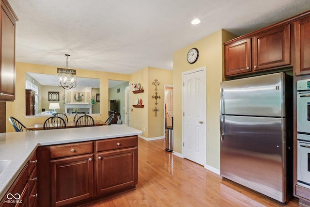 9311 Windrift Way, Zionsville, IN 46077 - kitchen featuring appliances with stainless steel finishes, light wood-type flooring, a chandelier, light countertops, and a peninsula