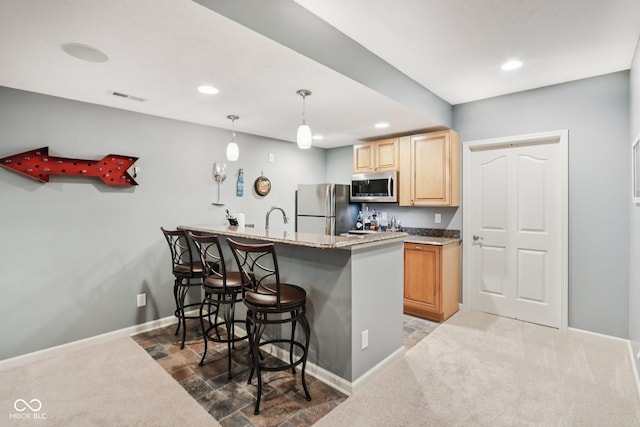 9311 Windrift Way, Zionsville, IN 46077 - kitchen with stainless steel appliances, a kitchen bar, recessed lighting, light brown cabinets, and carpet