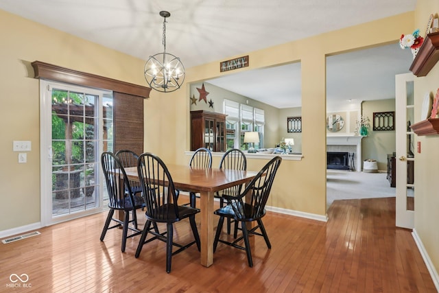 9311 Windrift Way, Zionsville, IN 46077 - dining area with a chandelier, healthy amount of natural light, wood-type flooring, and a tiled fireplace