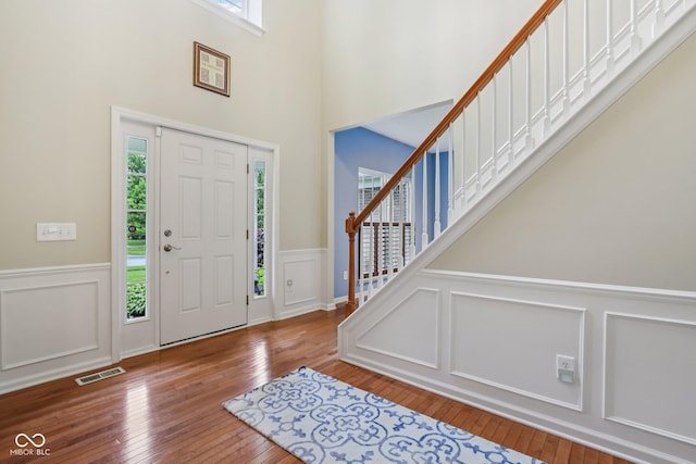 9311 Windrift Way, Zionsville, IN 46077 - entrance foyer with wood-type flooring, a wainscoted wall, stairway, a decorative wall, and a high ceiling