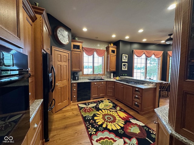 125 Ems B20C Ln, Pierceton, IN 46562 - kitchen with black appliances, a peninsula, light wood finished floors, brown cabinetry, and glass insert cabinets