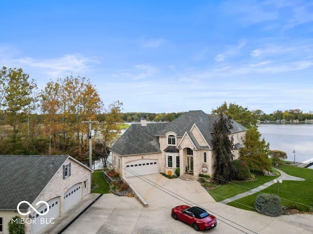 125 Ems B20C Ln, Pierceton, IN 46562 - view of front facade with stone siding, concrete driveway, a chimney, a front yard, and a water view