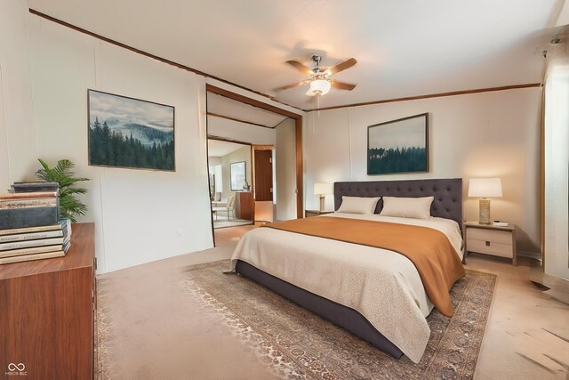 bedroom with crown molding, light colored carpet, ensuite bathroom, and a ceiling fan