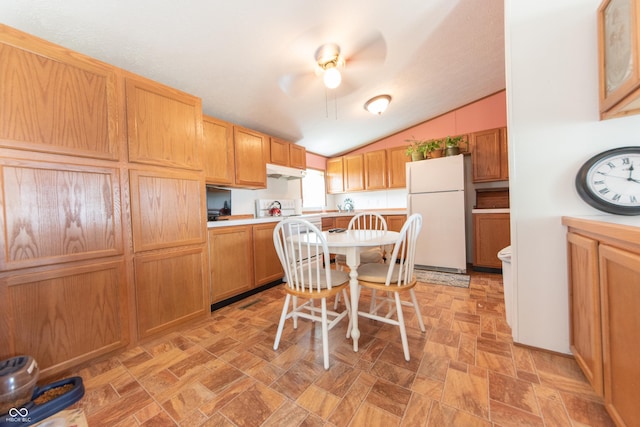 kitchen with freestanding refrigerator, vaulted ceiling, light countertops, under cabinet range hood, and ceiling fan