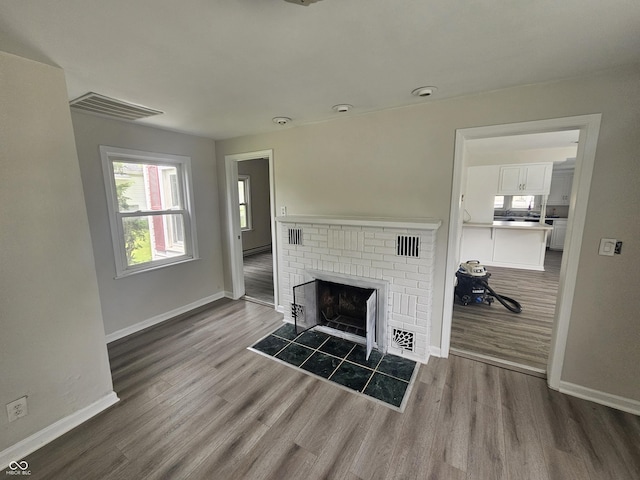 208 S Madison St, Converse, IN 46919 - living room featuring baseboards, wood finished floors, a brick fireplace, and a baseboard radiator