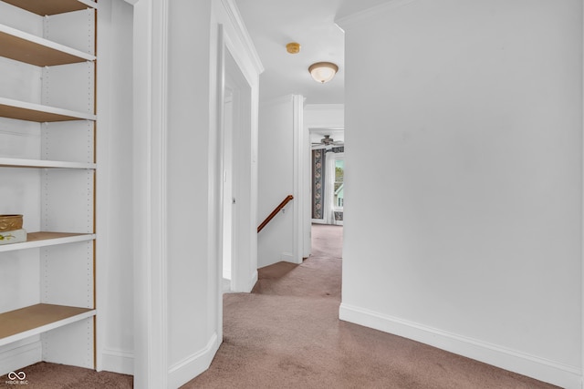 hallway featuring carpet flooring, an upstairs landing, baseboards, and ornamental molding
